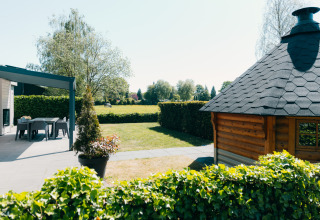 Zona exterior en Veluwe Villa, Holiday park De Boshoek, Países Bajos, con terraza y cabaña de madera.
