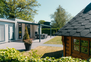 Lodge Veluwe Villa en Holiday park De Boshoek, Países Bajos, con terraza, jardín y cabaña de madera delante.