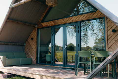 Vue extérieure de la Big Lodge au Holiday park De Boshoek, Pays-Bas, terrasse et mobilier moderne visibles.