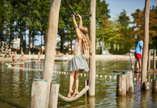 Kind spielt auf einem Seilparcours über Wasser im Ferienpark De Leistert in Limburg, Niederlande.