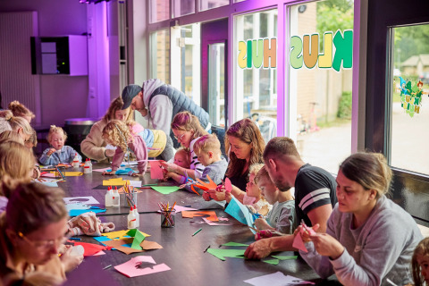 Kinderen en volwassenen knutselen samen aan tafel bij De Leistert vakantiepark in Limburg, Nederland.