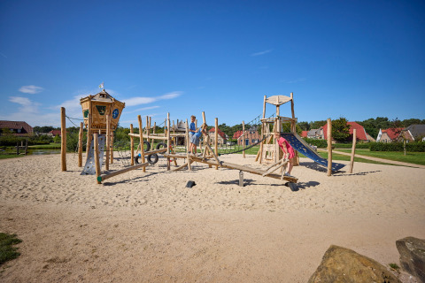 Kinderen spelen op een speeltuin met glijbaan en klimtoestel in vakantiepark De Leistert, Limburg, Nederland.