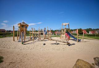 Kinderen spelen op een speeltuin met glijbaan en klimtoestel in vakantiepark De Leistert, Limburg, Nederland.