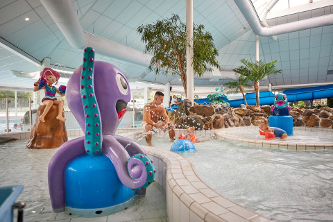 Parc aquatique intérieur à De Leistert, Limburg, Pays-Bas, avec des enfants jouant parmi des statues ludiques.