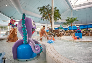 Parc aquatique intérieur à De Leistert, Limburg, Pays-Bas, avec des enfants jouant parmi des statues ludiques.