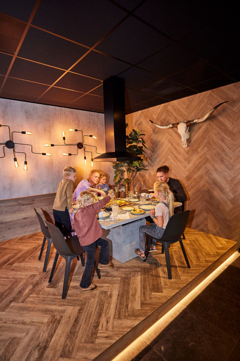 Gezin dineert samen aan een moderne tafel in vakantiepark De Leistert, Limburg, Nederland.