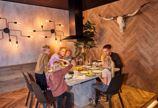 Family enjoys a meal together at a modern table in the De Leistert holiday park, Limburg, Netherlands.