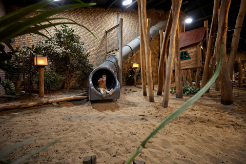 Binnenspeeltuin met glijbaan en boomhut in vakantiepark De Leistert, Limburg, Nederland.