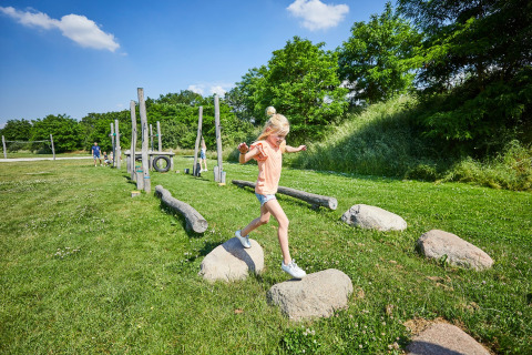 Een kind speelt op een outdoor hindernissenparcours in vakantiepark De Leistert, Limburg, Nederland, bij zonneschijn.