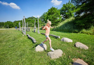 Een kind speelt op een outdoor hindernissenparcours in vakantiepark De Leistert, Limburg, Nederland, bij zonneschijn.