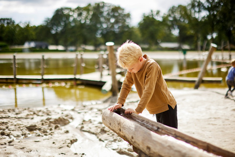 Junge spielt an einem Sand- und Wasserbereich im Ferienpark De Leistert in Limburg, Niederlande.