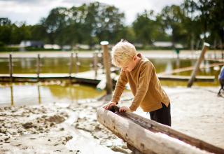 Boy playing at a sand and water area in De Leistert holiday park, Limburg, Netherlands, sunny day.