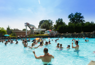 People swimming and playing in the pool with a waterslide at De Leistert holiday park in Limburg, Netherlands.