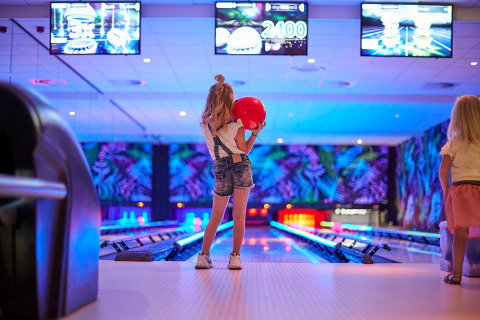 Twee kinderen bowlen in een kleurrijke bowlinghal van vakantiepark De Leistert in Limburg, Nederland.