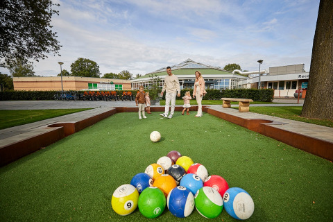 Een familie speelt buiten met grote ballen in vakantiepark De Leistert in Limburg, Nederland.