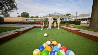 En familie leger på en udendørs bane med store kugler ved De Leistert feriepark i Limburg, Holland.