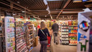 En familie handler i et supermarked i ferieparken De Leistert i Limburg, Holland med fyldte hylder.