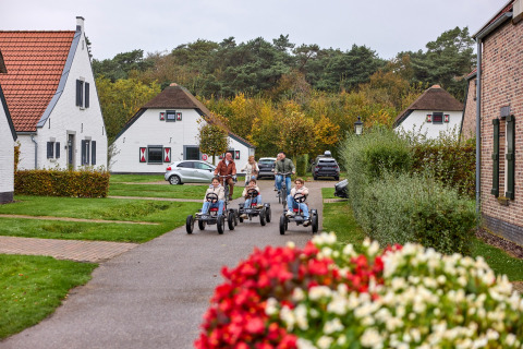 Familier nyder cykling og gokarts på en hyggelig vej i ferieparken De Leistert i Limburg, Holland.