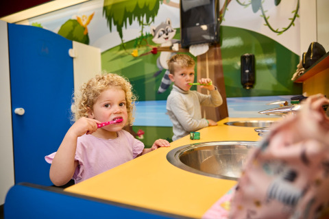 Kinderen poetsen hun tanden aan een vrolijk wasbekken in een vakantiepark in Limburg, Nederland.