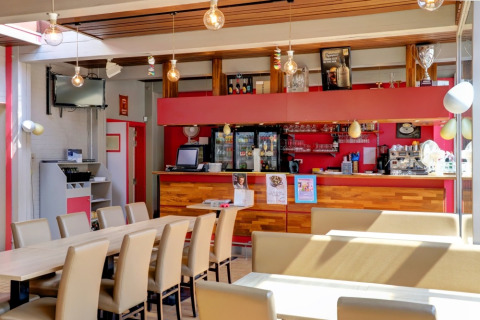 Caffetteria luminosa e moderna con zona bar in un villaggio vacanze con sistemazioni glamping.