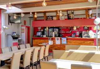 Caffetteria luminosa e moderna con zona bar in un villaggio vacanze con sistemazioni glamping.