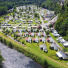 Aerial view of a holiday park featuring glamping accommodations, cabins, and riverside greenery.