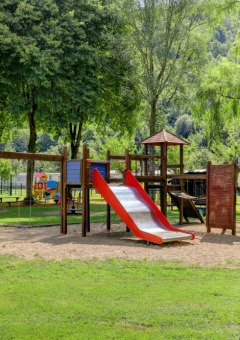 Spielplatz in einem Ferienpark mit Glamping-Unterkünften, umgeben von viel Grün und Bäumen.