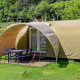 Tenda safari chiamata Coco Sweet con veranda coperta e tavolo all'aperto, immersa nel verde.