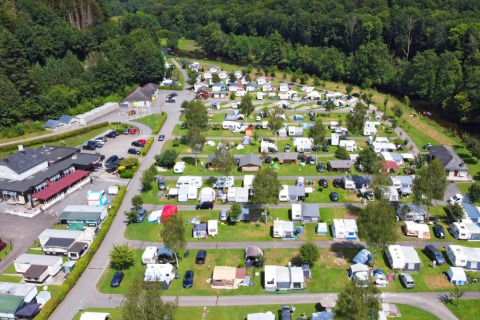 Aerial view of a holiday park featuring caravans, glamping accommodations, and greenery by a forest.