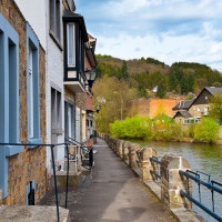 Bild eines Ferienparks am Fluss mit traditionellen Häusern und viel Natur, ideal für Glamping-Aufenthalte.