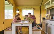 Family spending quality time at a wooden table inside the Safari Tent at De Leistert in the Netherlands.