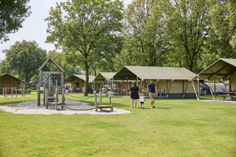 Familie auf einem Campingplatz mit Safari-Zelten und Spielplatz bei De Leistert in den Niederlanden.