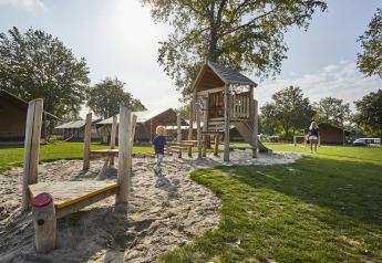 Børnelegeplads foran safaritelte på De Leistert campingpladsen i Holland på en solrig dag.