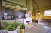 Child using a mobile device inside the Safari Tent at De Leistert, Netherlands, with game board and kitchen.