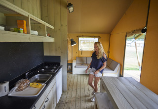 Vrouw in een moderne safaritent met keuken en zithoek bij De Leistert in Nederland.