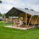 Famiglia si rilassa davanti a una tenda safari Glamping Tent Comfort in un campeggio verde e soleggiato.