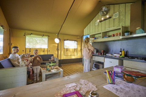 Gezin geniet samen in de Glamping Tent Comfort bij De Leistert, Nederland, compleet met keuken en spelletjes.