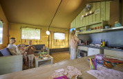Family spends time together inside the Glamping Tent Comfort at De Leistert, Netherlands, with cozy kitchen.