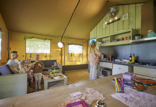 Family spends time together inside the Glamping Tent Comfort at De Leistert, Netherlands, with cozy kitchen.