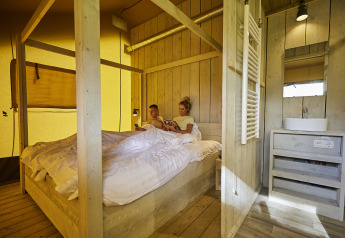 Inde i en komfortabel glamping-telt på De Leistert, Holland, slapper et par af i en hyggelig seng.