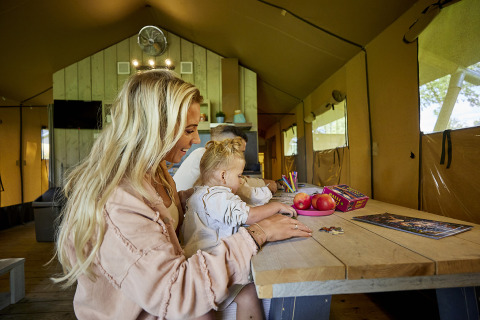 Een gezin geniet van puzzelen en creatieve activiteiten in een Glamping Tent Comfort bij De Leistert.
