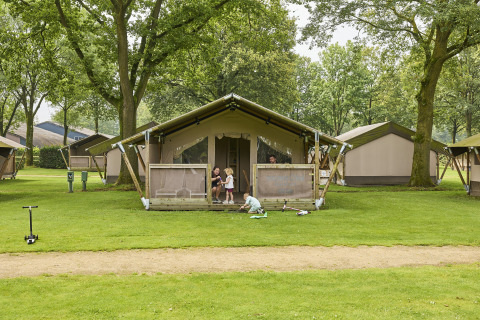 Gezin geniet van buitenactiviteiten voor een Kalahari safaritent op De Leistert camping.