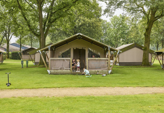 Family playing and relaxing outside a Kalahari safari tent at De Leistert campsite in the Netherlands.