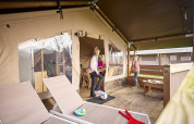Children playing on the porch of a Kalahari safari tent at De Leistert in the Netherlands, modern and spacious.
