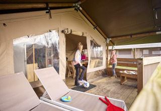 Children playing on the porch of a Kalahari safari tent at De Leistert in the Netherlands, modern and spacious.