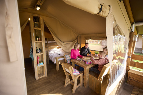 Gezin speelt gezelschapsspel in een Kalahari Safaritent bij De Leistert in Nederland, gezellige glamping sfeer.