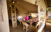 Family playing board games inside a cozy Kalahari Safari tent at De Leistert in the Netherlands, glamping.