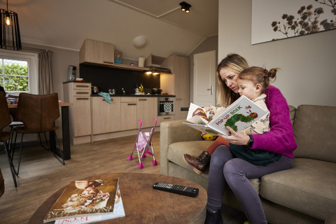 Moeder en dochter lezen een pop-up boek in de gezellige living van Leistert Lodge, De Leistert, Nederland.