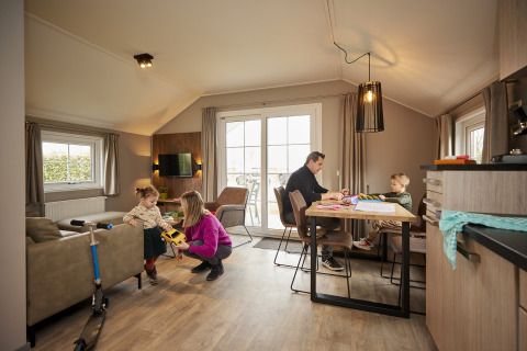 Gezin aan het genieten in Leistert Lodge, De Leistert, Nederland, met spelende kinderen en ontspannen ouders.