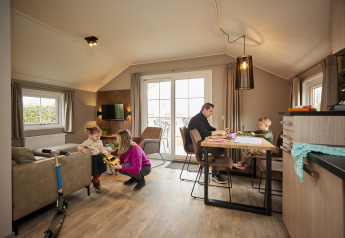Gezin aan het genieten in Leistert Lodge, De Leistert, Nederland, met spelende kinderen en ontspannen ouders.